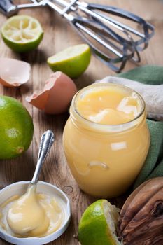 Jar of homemade lime curd with a spoon on old wooden background. Selective focus