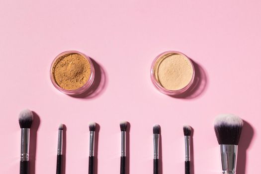 Various make-up brushes on pink background, top view. Cosmetics and beauty