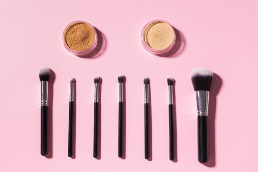 Various make-up brushes on pink background, top view. Cosmetics and beauty