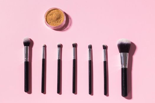 Various make-up brushes on pink background, top view. Cosmetics and beauty