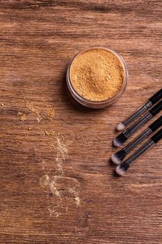 Mineral powder foundation with brush on a wooden background.