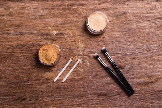 Mineral powder foundation with brush on a wooden background.