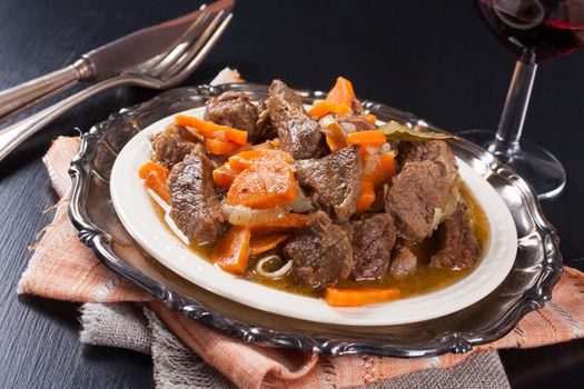 Plate of beef stew with a green salad on dark background. Very Shallow depth of field.