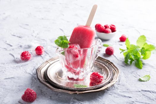 Homemade raspberry popsicles in glass with ice, raspberries and mint. Summer healty food concept.