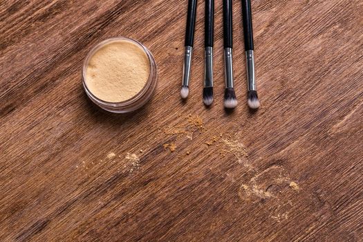 Mineral powder foundation with brush on a wooden background.