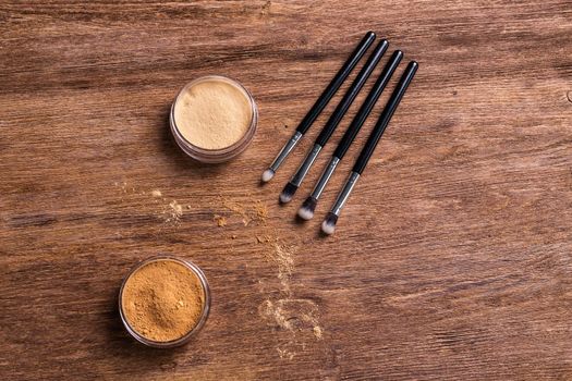 Mineral powder foundation with brush on a wooden background.