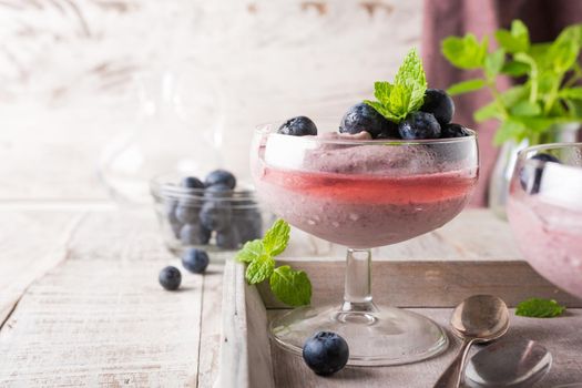 Glass of homemade healthy blueberry dessert with syrup and fresh berries.