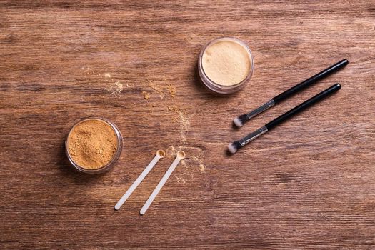 Mineral powder foundation with brush on a wooden background.