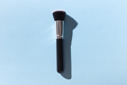 Make up brush on blue background, top view