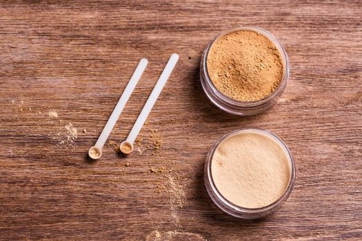 Mineral powder of different colors with spoon dispenser for make-up on wooden background.