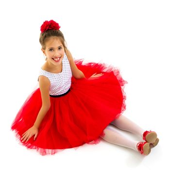 Little girl is sitting on the floor. The concept of a happy childhood. Isolated on white background.