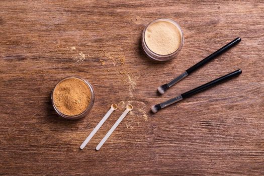 Mineral powder foundation with brush on a wooden background.