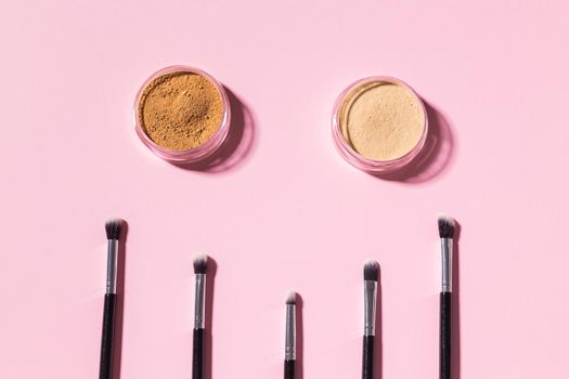 Various make-up brushes on pink background, top view. Cosmetics and beauty