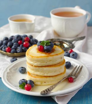 Stack of pancakes with fresh berries and honey