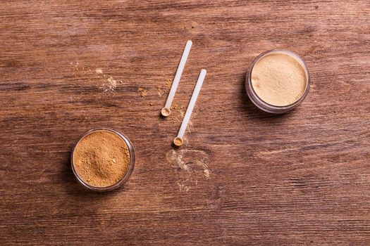 Mineral powder of different colors with spoon dispenser for make-up on wooden background.