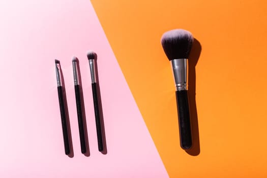 Various make-up brushes on pink background, top view. Cosmetics and beauty