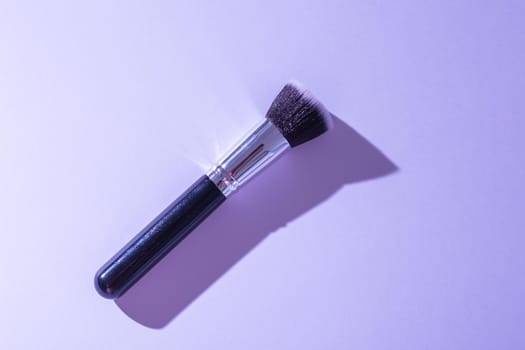 Make up brush on turquoise background, top view