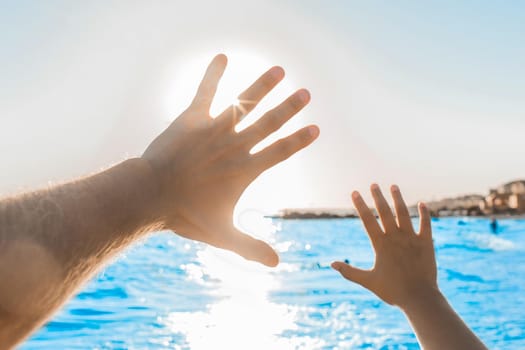 The silhouette of the man's hands and the chewing arms waving against the bright sunny sky, the blue sea and the horizon line.