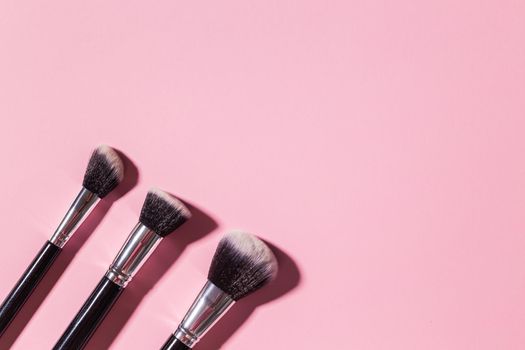 Various make-up brushes on pink background, top view. Cosmetics and beauty