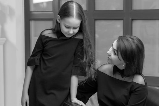 Happy family, mom and daughter near a large panoramic window, in the studio.