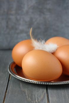 Fresh eegs on metal plate on rustic wooden background