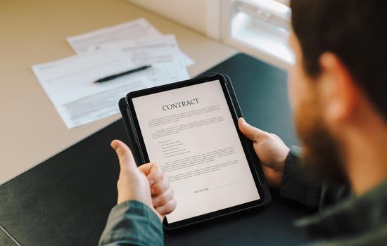 Man reaidng contract template on tablet at office and showing thumbs up. Concept of documents filling and sample.