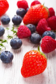 Close up of strawberry and ather berries on White Wooden Background. Summer or Spring Organic Berry over Wood. Strawberries, Raspberries, Blueberry and thyme. Helthy food, Gardening, Harvest Concept.