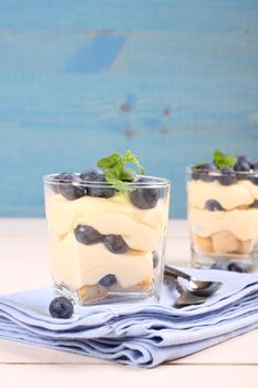 Fresh blueberry layered desert with mascarpone cream and cookies in glass