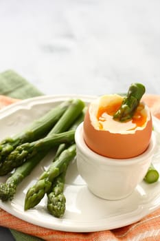 Green asparagus with soft-boiled egg on white plate