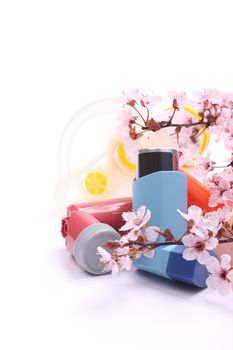 Asthma inhalers with extension tube for children and blossoming tree branches over white