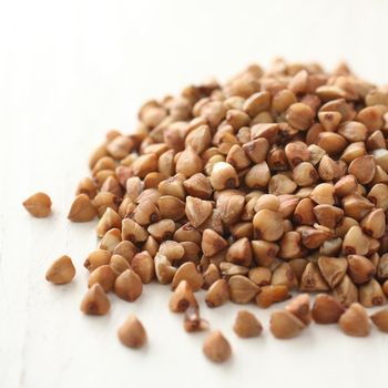 Pile of buckwheat grain on white wooden background