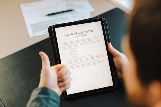 Man reading payment agreement contract on tablet at office and showing thumbs up. Concept of law and documents filling.