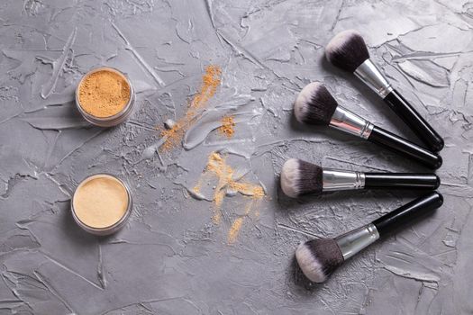 Mineral powder of different colors with a brushes for make-up on wooden background