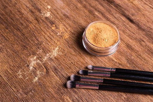 Mineral powder foundation with brush on a wooden background.