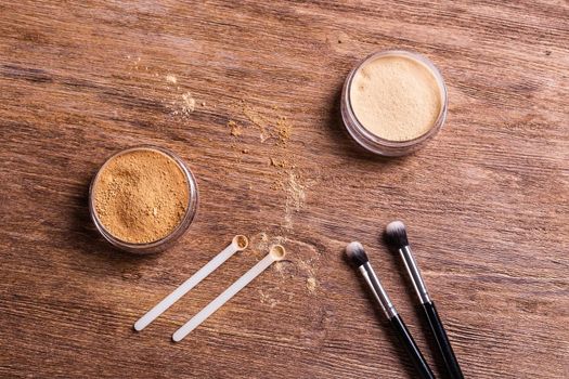 Mineral powder foundation with brush on a wooden background.