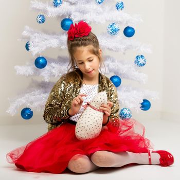 Beautiful little girl near the Christmas tree. The concept of family holidays, children's emotions.