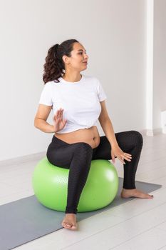 Cheerful pregnant woman dances while sitting on fitness ball. Well-being pregnancy, healthy lifestyle and positive concept