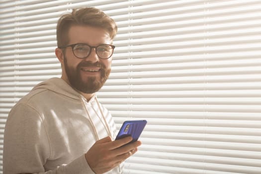 Happy man using mobile phone at home or at office.