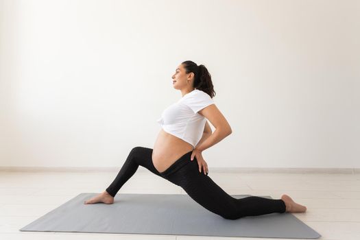 Purposeful pregnant woman exercises during yoga class and relaxes while sitting on a mat on the floor. Physical and mental preparation of the body for childbirth. Place for text