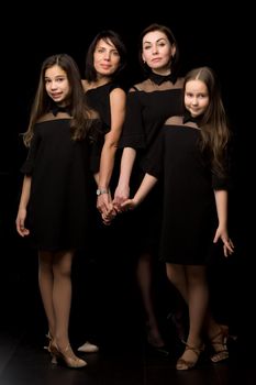 Group portrait on a black background. Young, Beautiful mothers with two charming daughters.