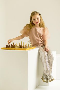 A little girl is playing chess. The concept of creative education of a child, training of thinking.