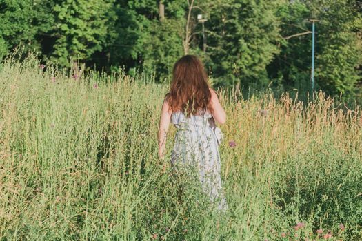 Woman walking in a field in summer sunny day.