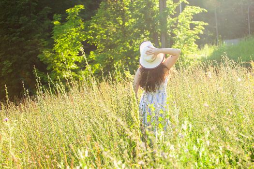 Woman walking in a field in summer sunny day.