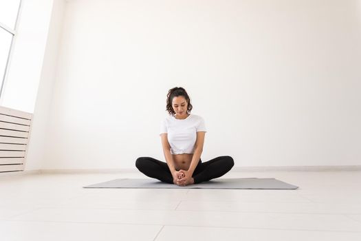 Purposeful pregnant woman exercises during yoga class and relaxes while sitting on a mat on the floor. Physical and mental preparation of the body for childbirth. Place for text