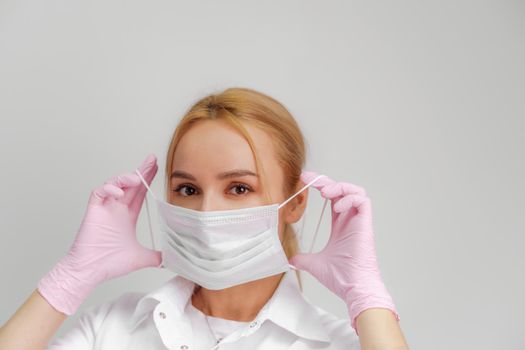 The doctor puts on a mask. Close-up portrait of medical staff. A woman in a protective mask .Isolated on a white background. Healthcare, cosmetology and medical concept.