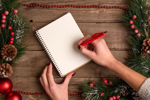 New Year and Christmas mokcup. hand writing on a notebook with Xmas lights on wooden background, space for your text, copyspace. from above. Holiday winter planning concept. Flat lay style.