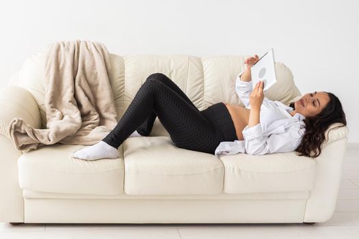 Latin pregnant woman using tablet computer sitting on sofa at home. Pregnancy and information for parenthood