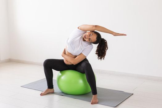 beautiful young pregnant woman doing exercise at home on fitball.