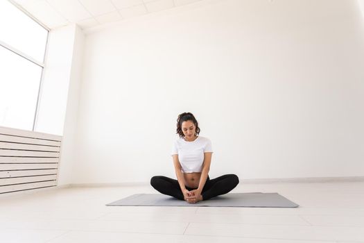 Healthy beautiful pregnant woman meditates before yoga class and relaxes while sitting on mat on the floor. Physical and mental preparation of body for childbirth. Copyspace