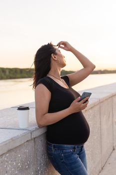 Pregnant woman feeling lovely and relax on embankment with warm light in morning